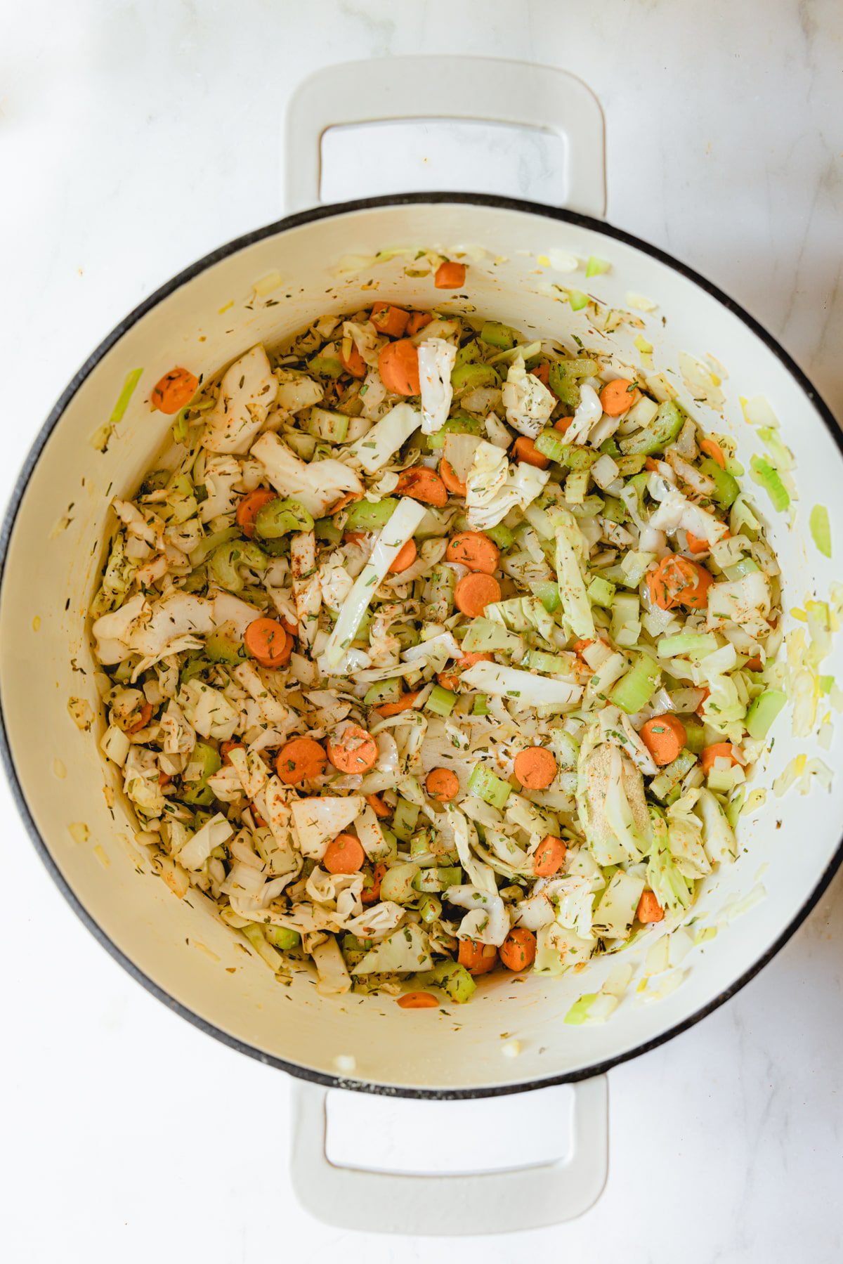 Dutch oven with veggies sautéing with olive oil.