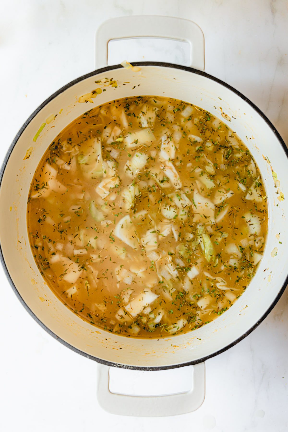 Vegetables and chicken stock in a dutch oven.