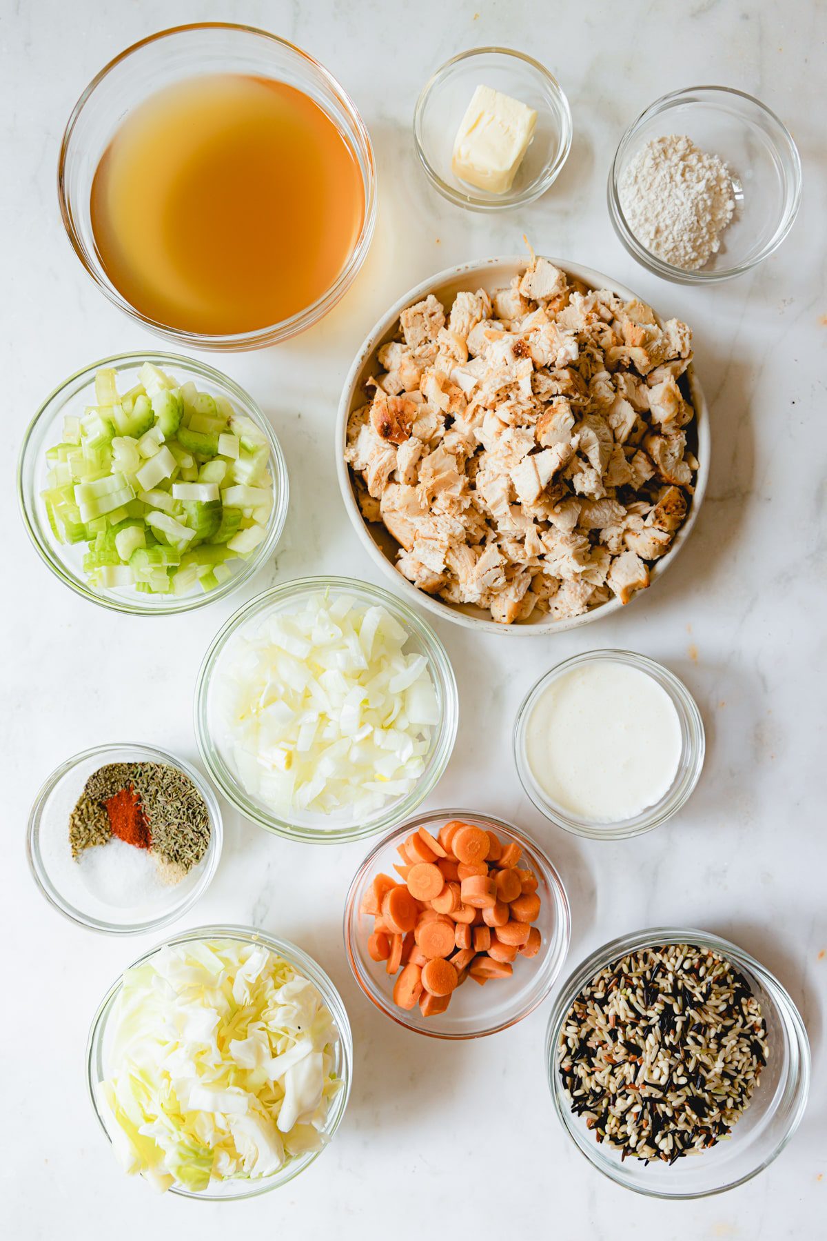 Chicken and wild rice soup ingredients in glass bowls.