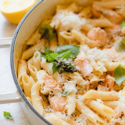 Skillet of pasta al salmone garnished with fresh basil.