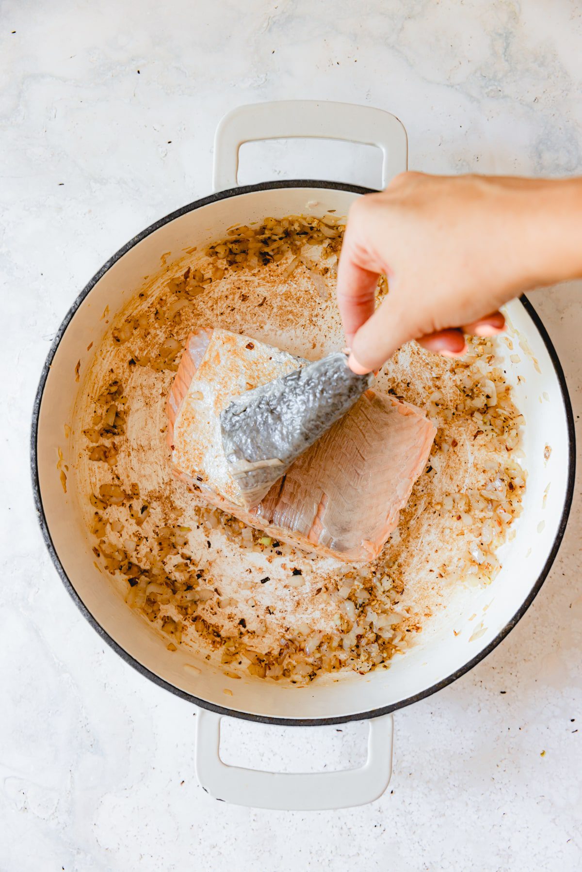 Pulling the skin off salmon in a skillet. 