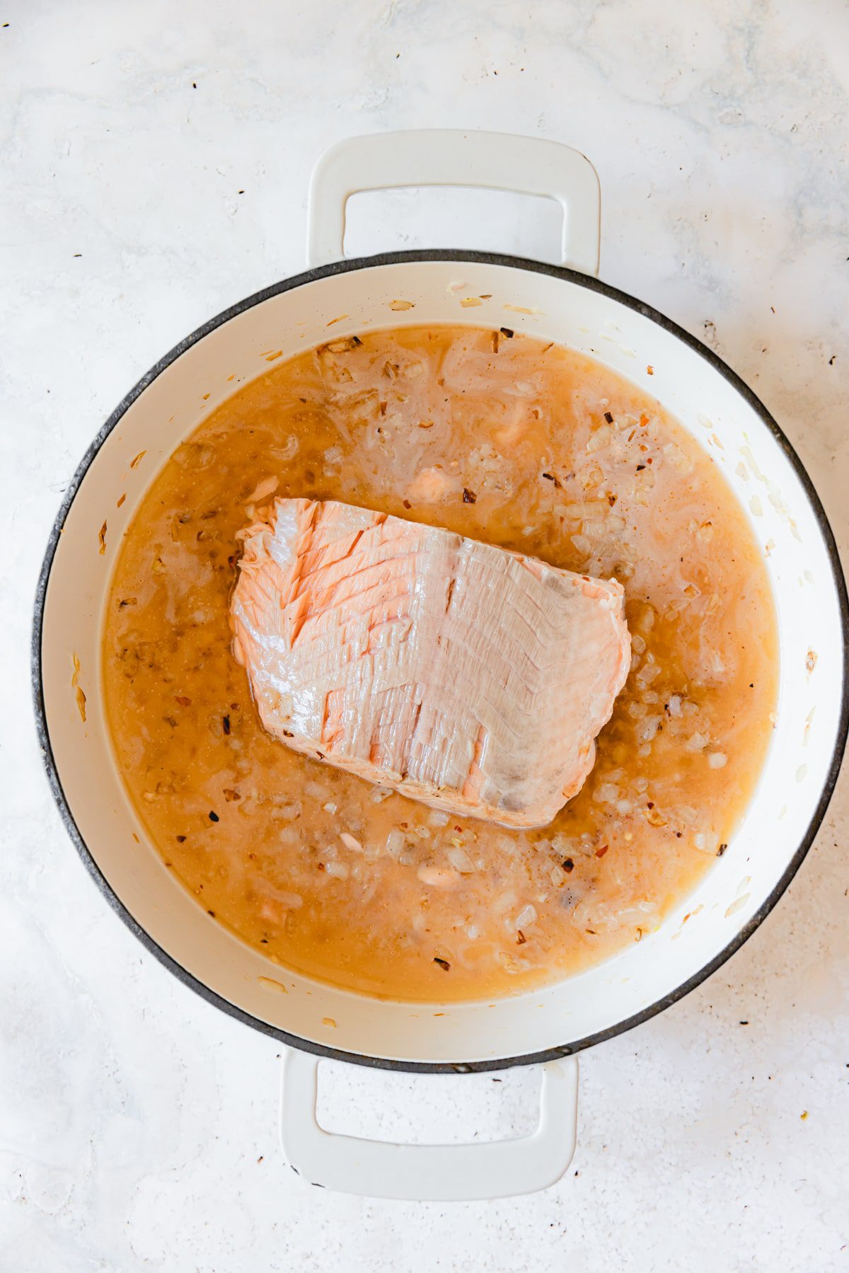 White wine, salmon, shallot, and garlic in a skillet. 