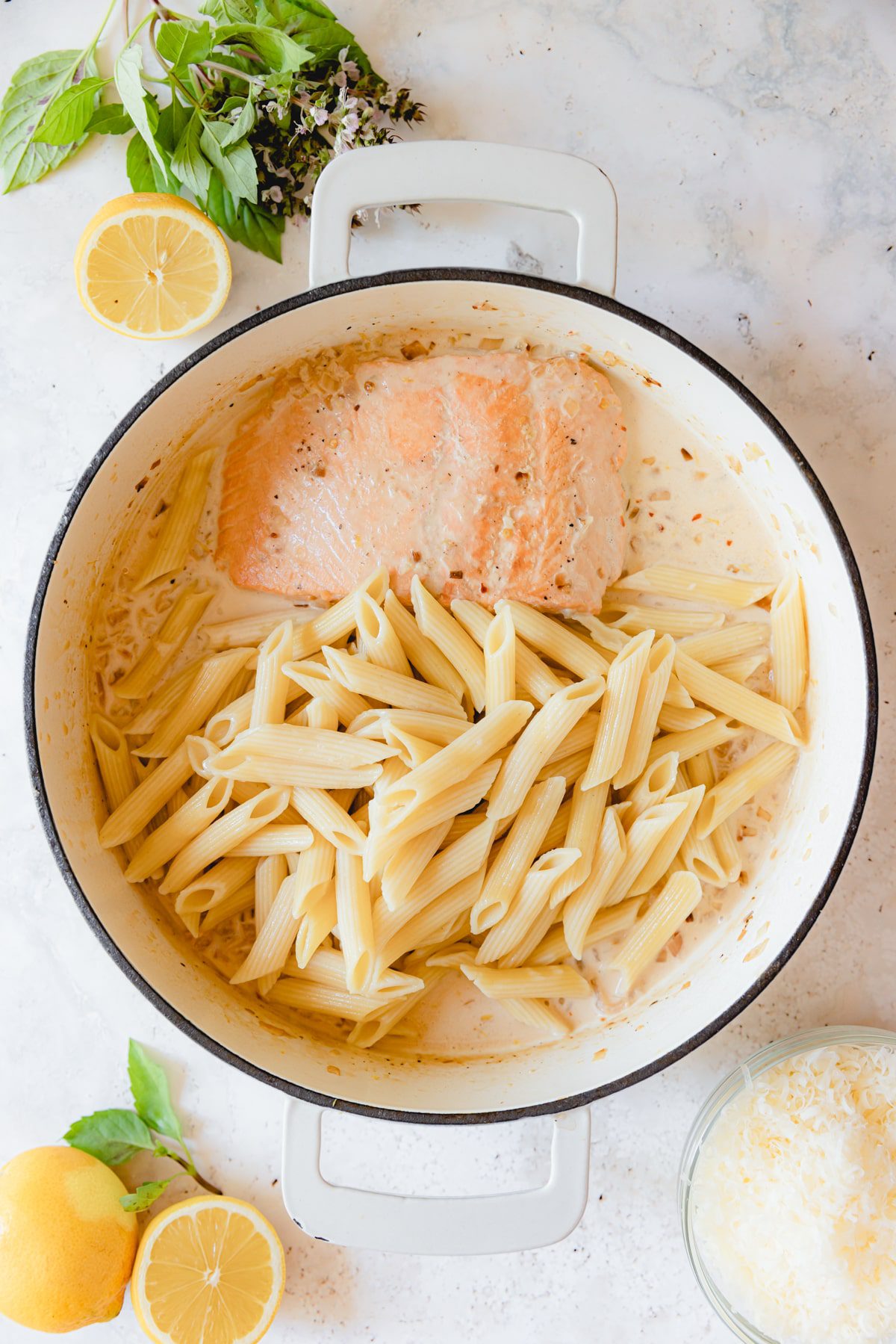 Pasta added to a skillet with salmon and cream sauce.  