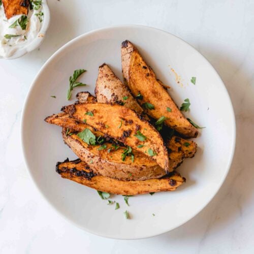 Seasoned air fried sweet potato wedges in a bowl.