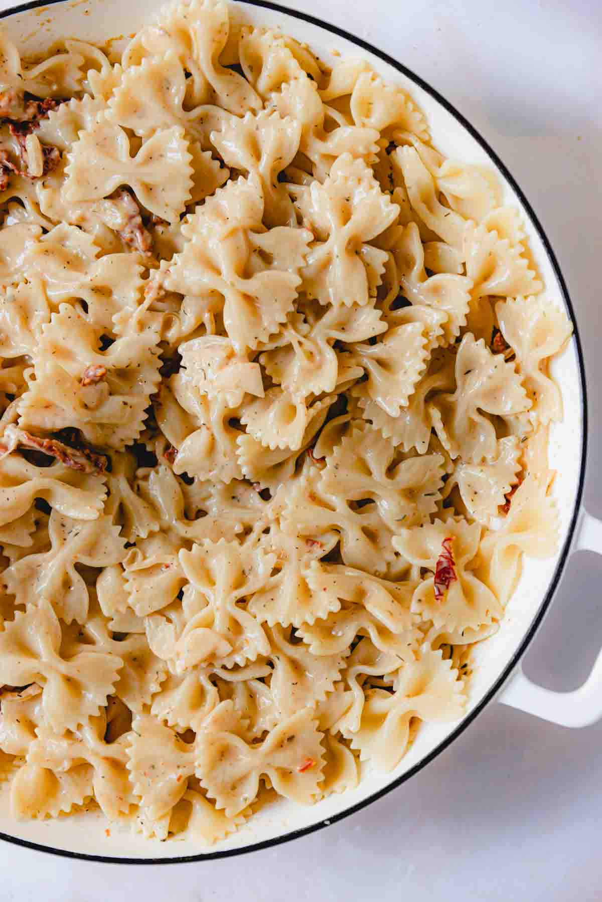 Bowtie pasta tossed together with the creamy sauce in a skillet. 