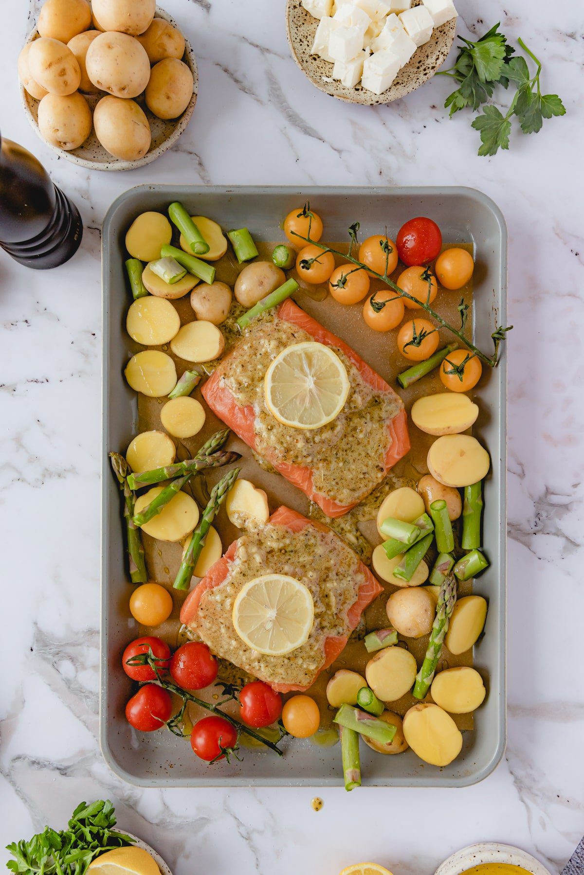 Raw salmon on a sheet tray with vegetables. 