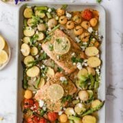 Cooked Mediterranean salmon on a sheet pan with lots of veggies.