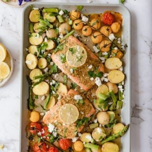 Cooked Mediterranean salmon on a sheet pan with lots of veggies.