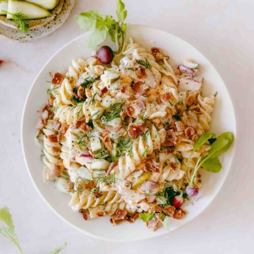 A square overhead shot of a bowl of dill pickle pasta salad.