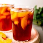 A side shot of glasses of peach iced tea on a wooden tray.