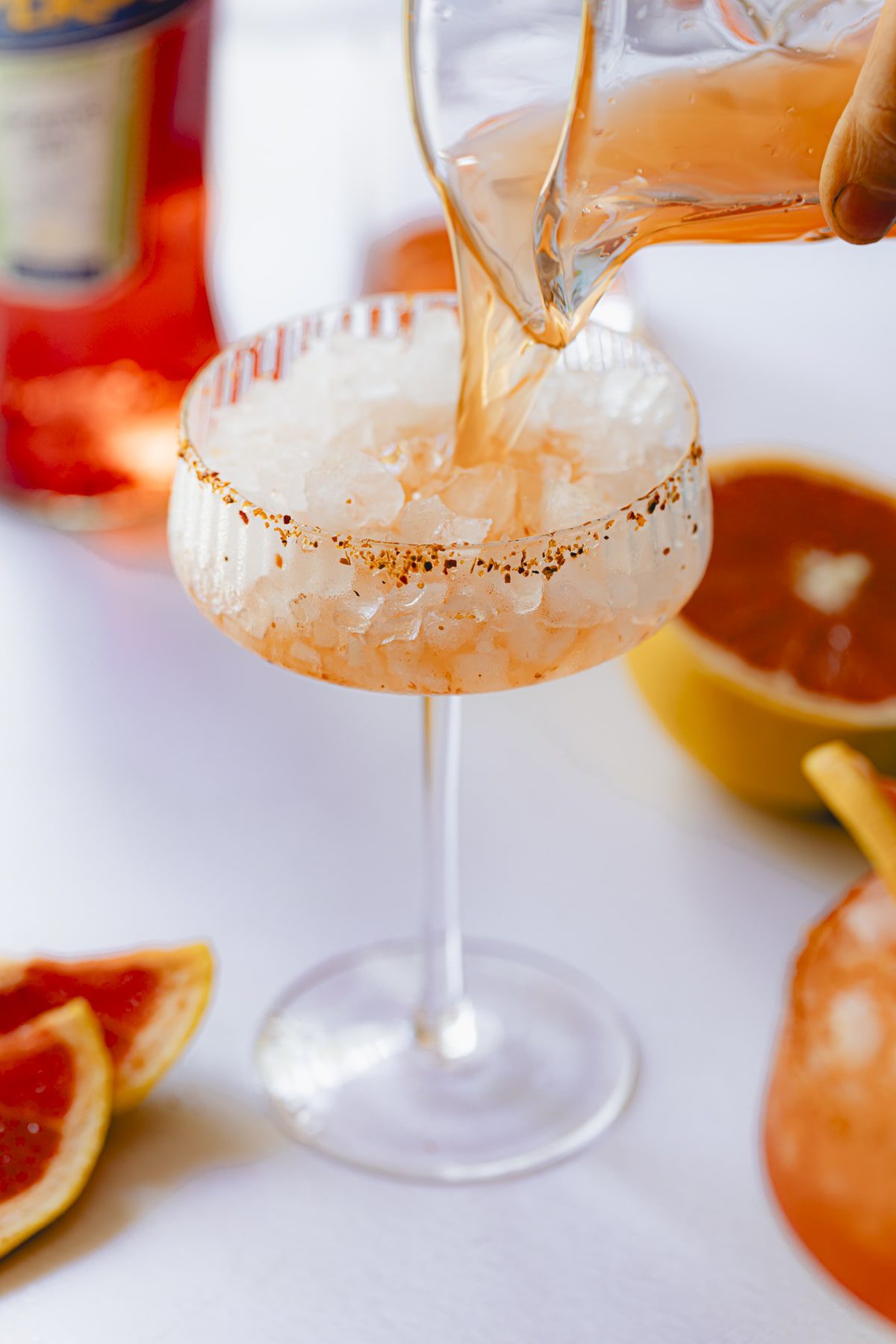 Pouring the Aperol, grapefruit, and tequila mixture into the glass of crushed ice.