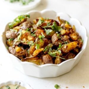 Red potatoes in a serving dish garnished with parsley and chives.