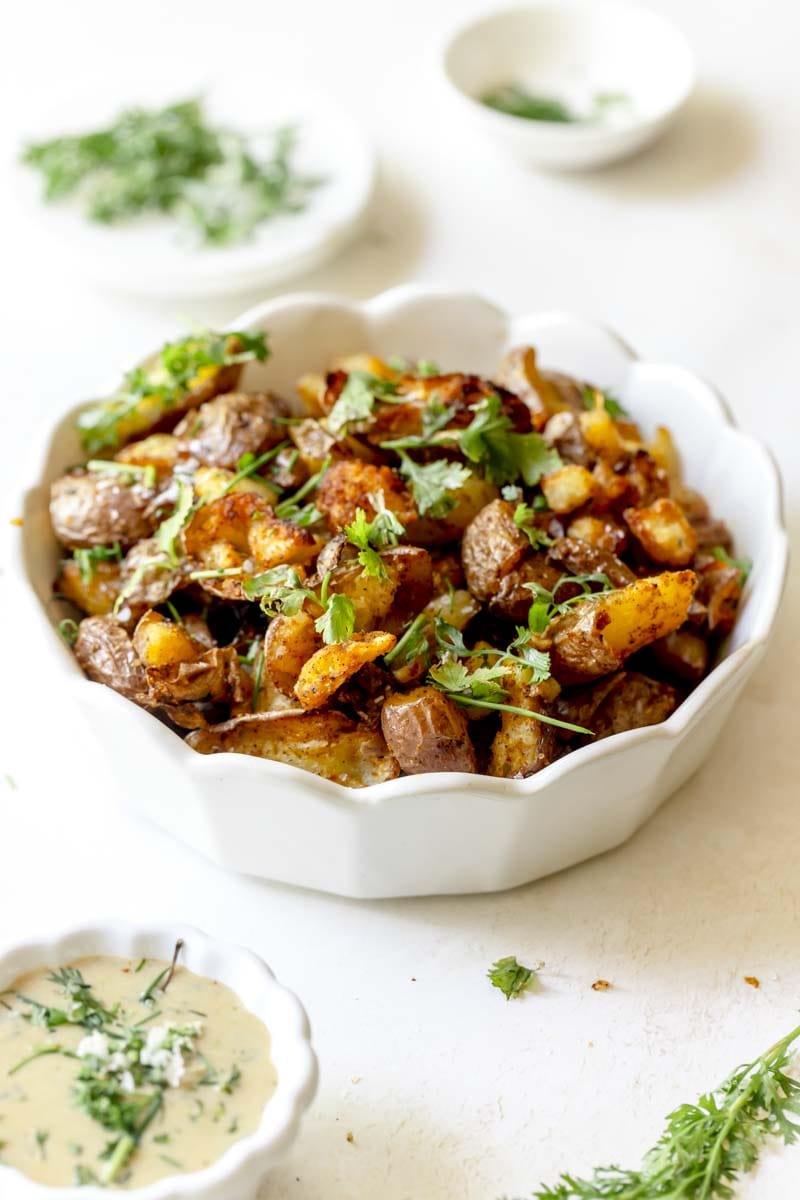 Red potatoes in a serving dish garnished with parsley and chives.