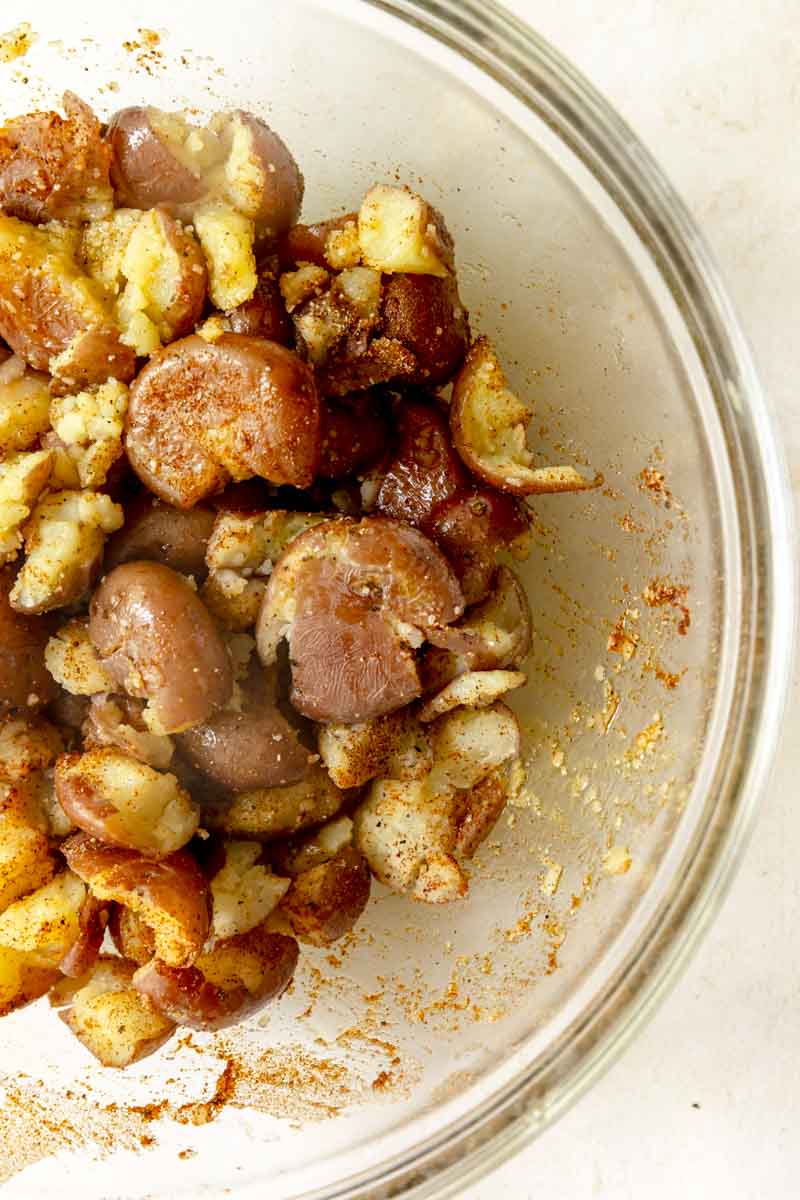 Tossing the red potatoes in a large bowl with olive oil and seasonings.