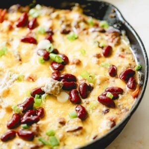 Chili cheese dip garnished with beans and green onion.