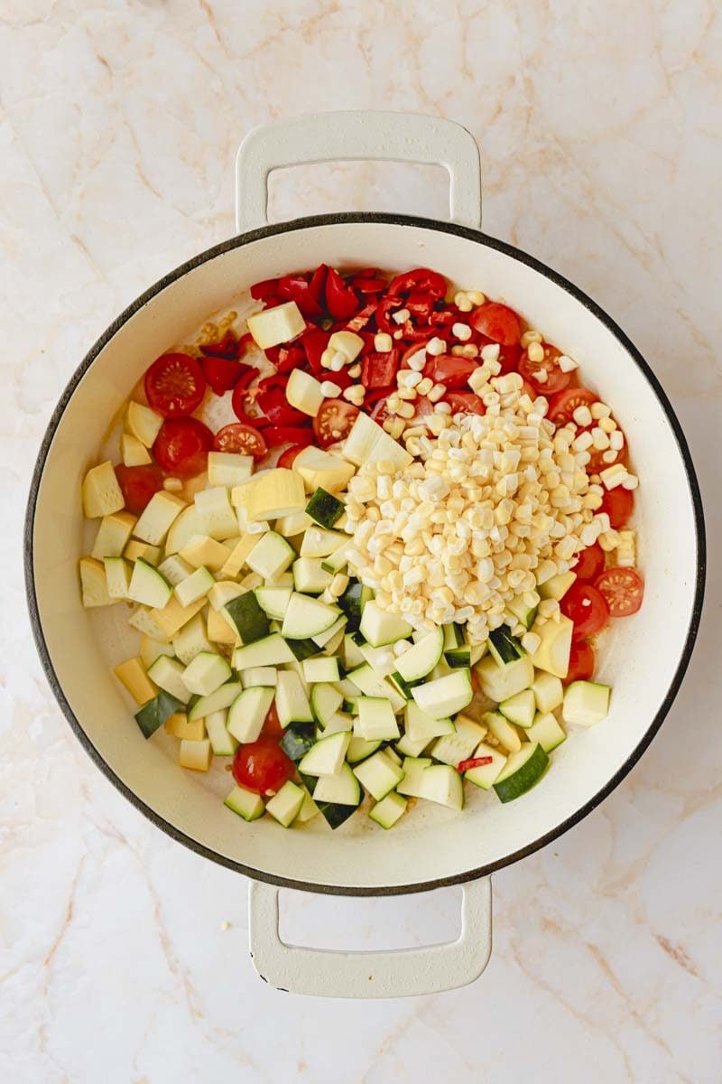 Add garlic, peppers, zucchini, corn and tomatoes in olive oil in a large skillet. 