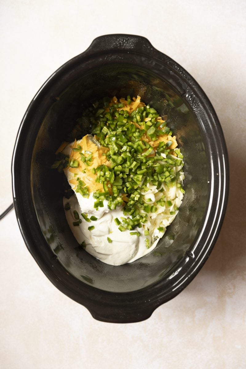 All ingredients for jalapeno popper dip uncooked in a crockpot. 