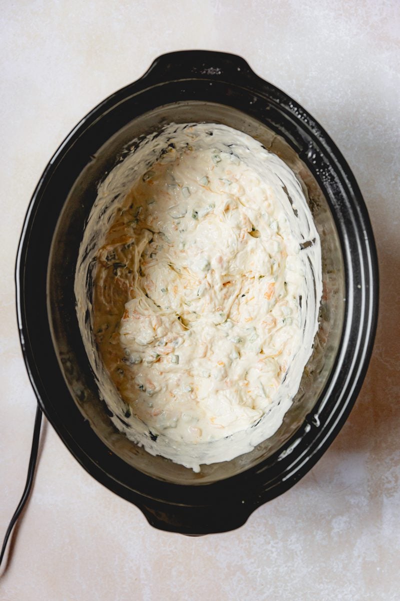 Cooked jalapeno popper dip in a crockpot stirred together. 