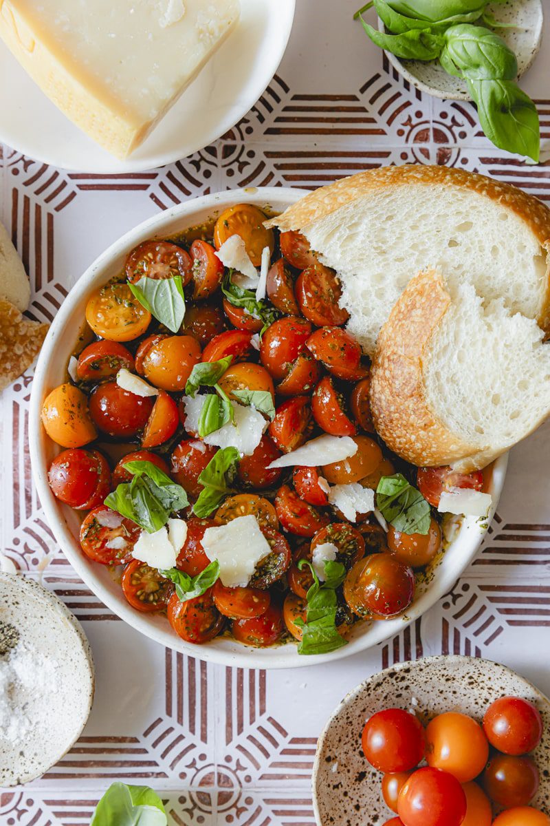 Plated bowl of Italian tomato salad garnished with basil and served with crusty bread.