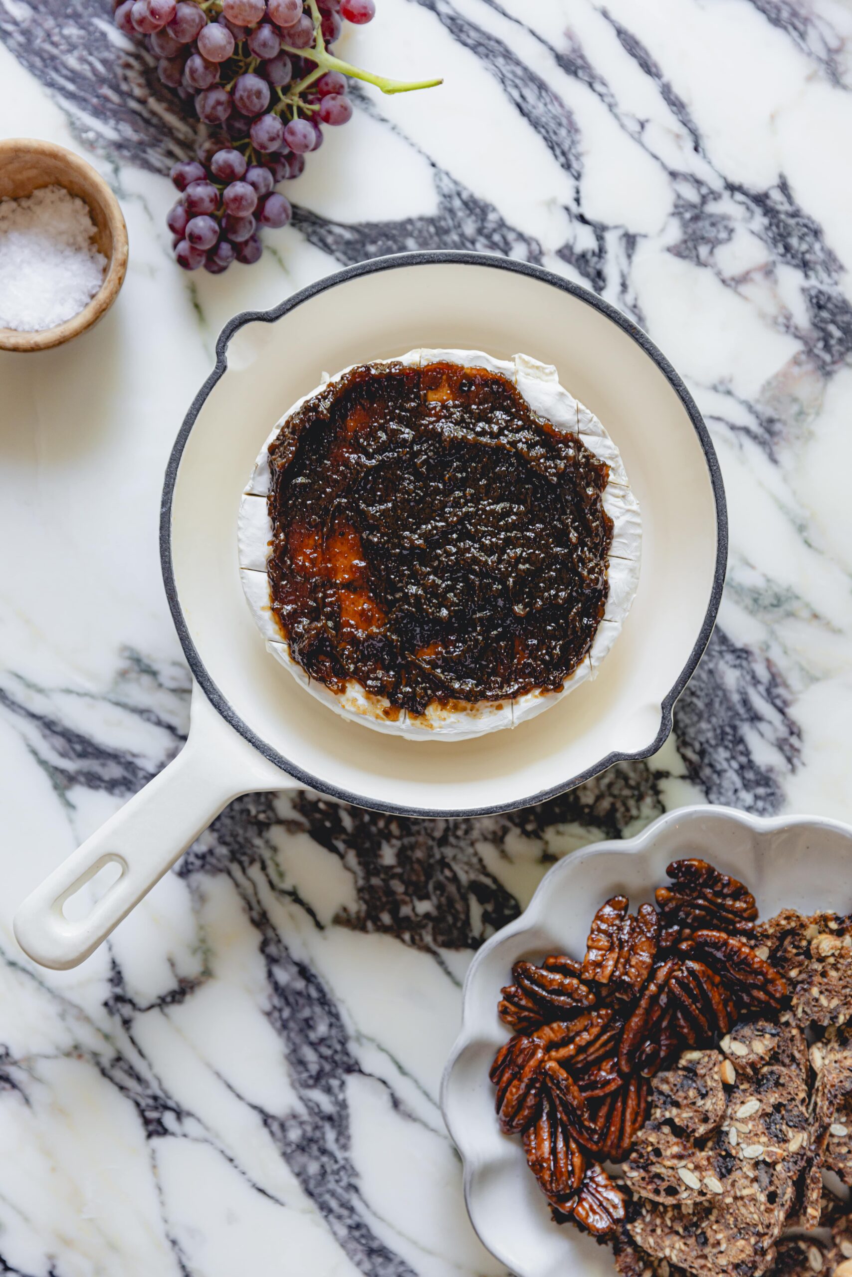 Fig jam spread on a wheel of brie in a skillet. 