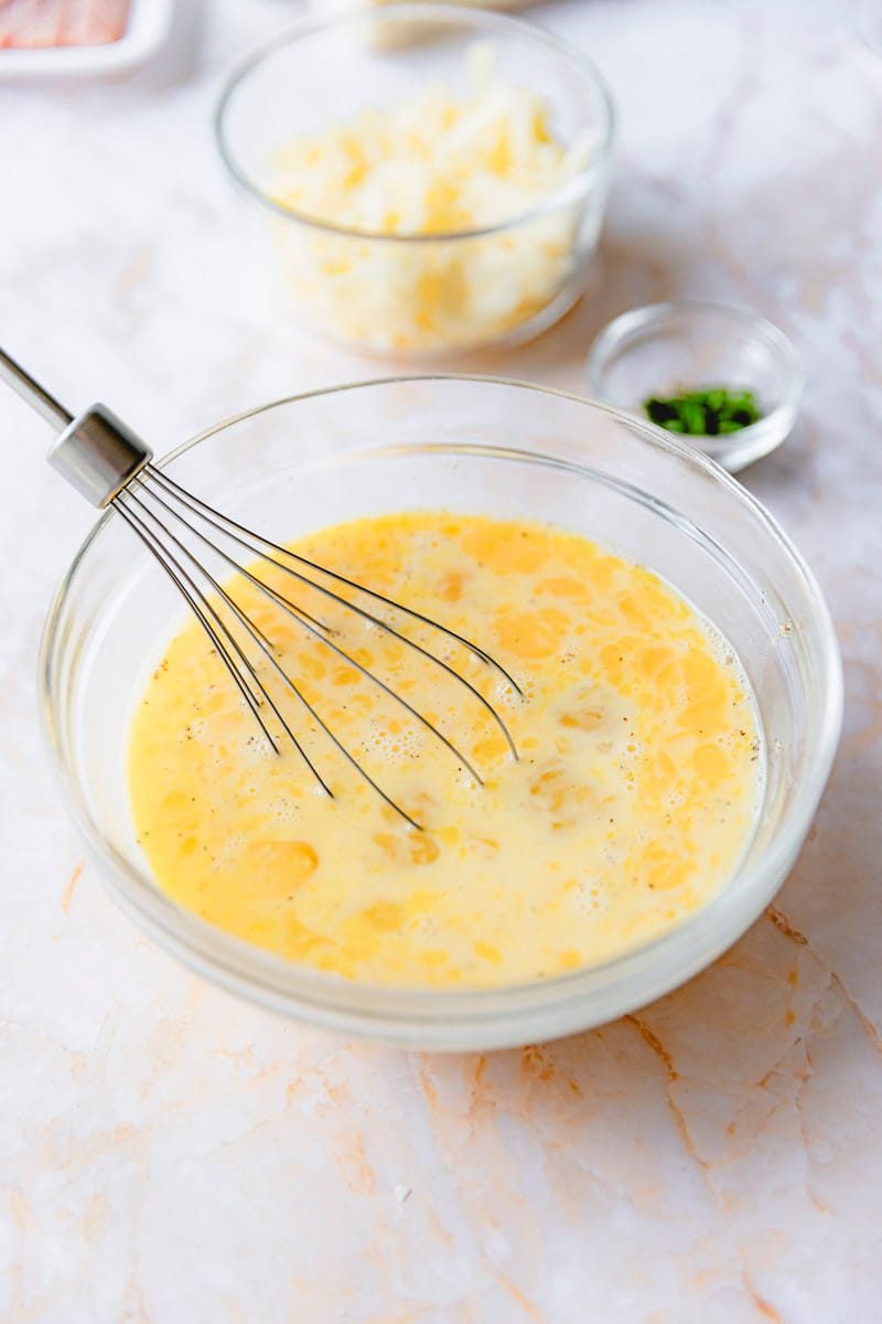 Eggs, milk, and spices whisked together in a bowl.