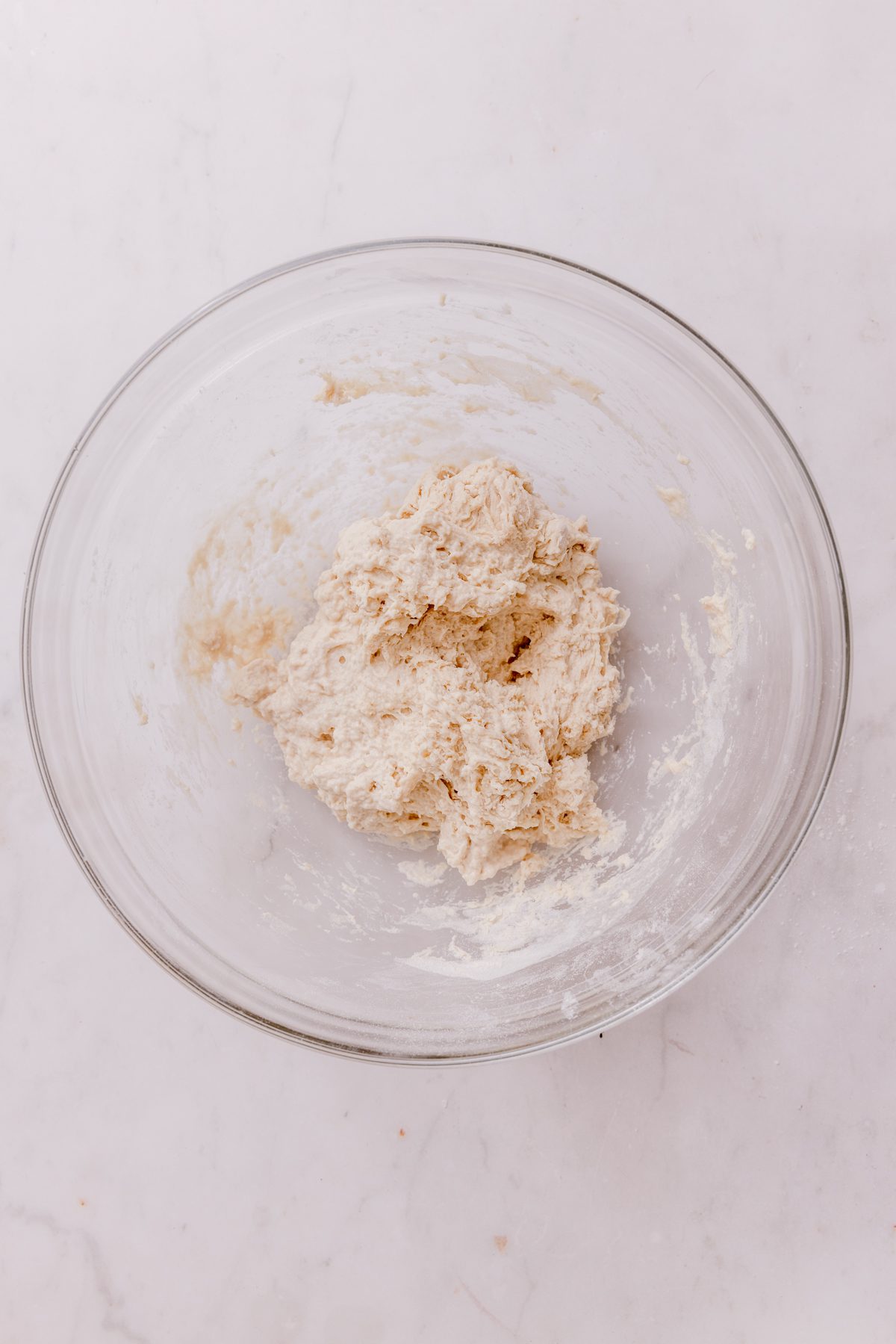Flour, water, and yeast stirred together in a glass bowl. 
