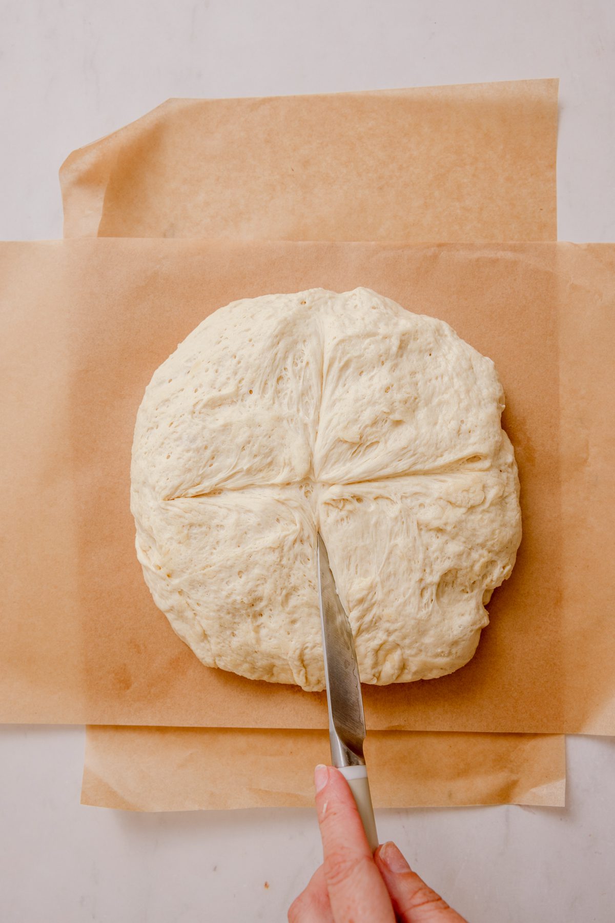 Slicing an x in dough on parchment.