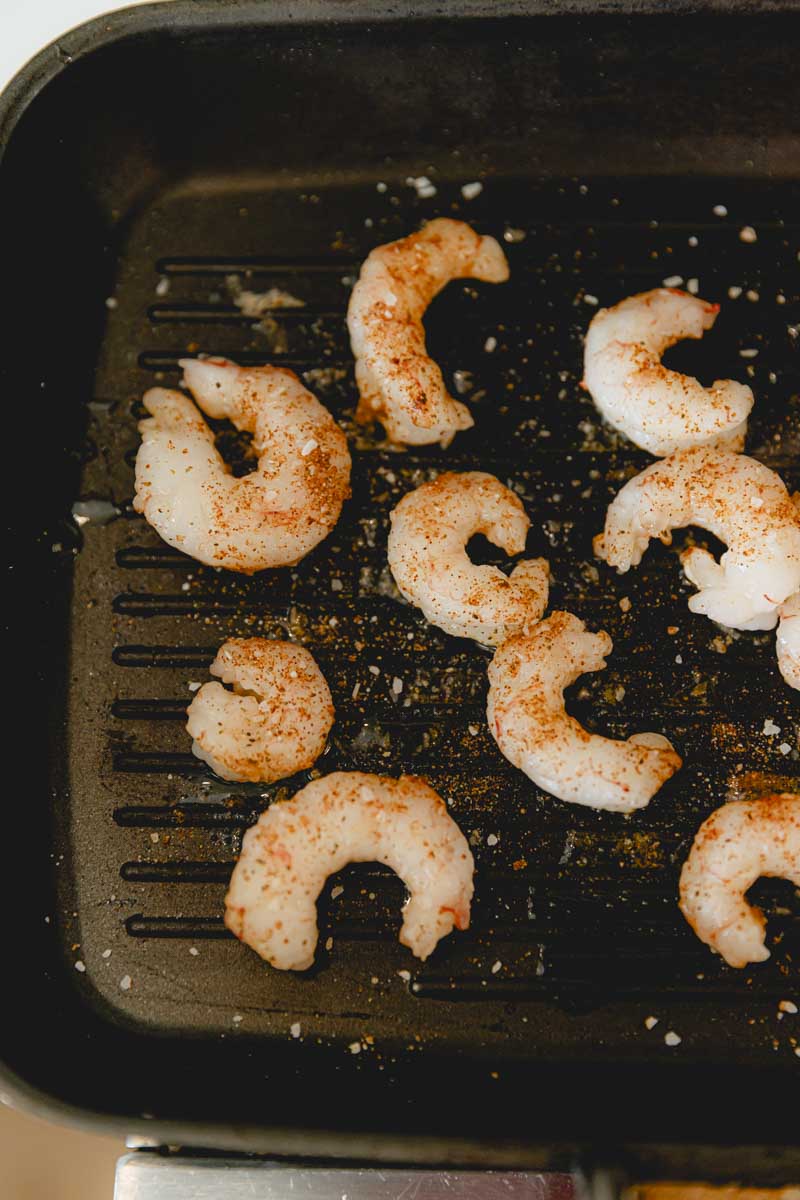 Cooking seasoned shrimp on a grill pan.