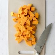 Cubed butternut squash on a cutting board with a knife.