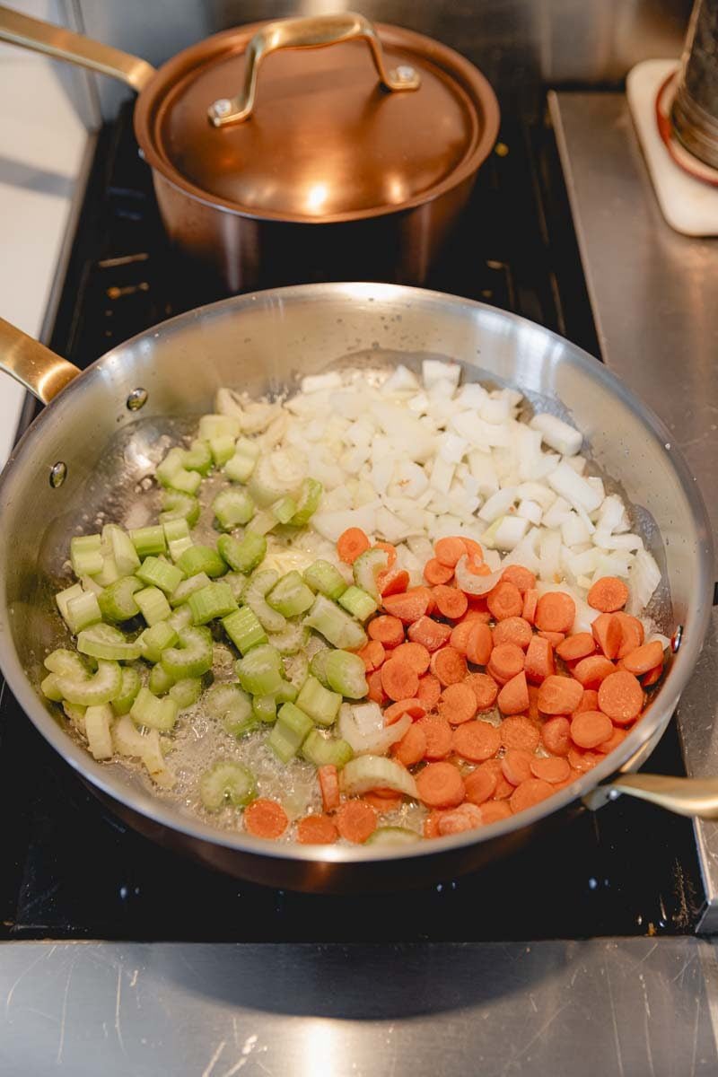 Onion, carrot, and celery sautéing in a pan.