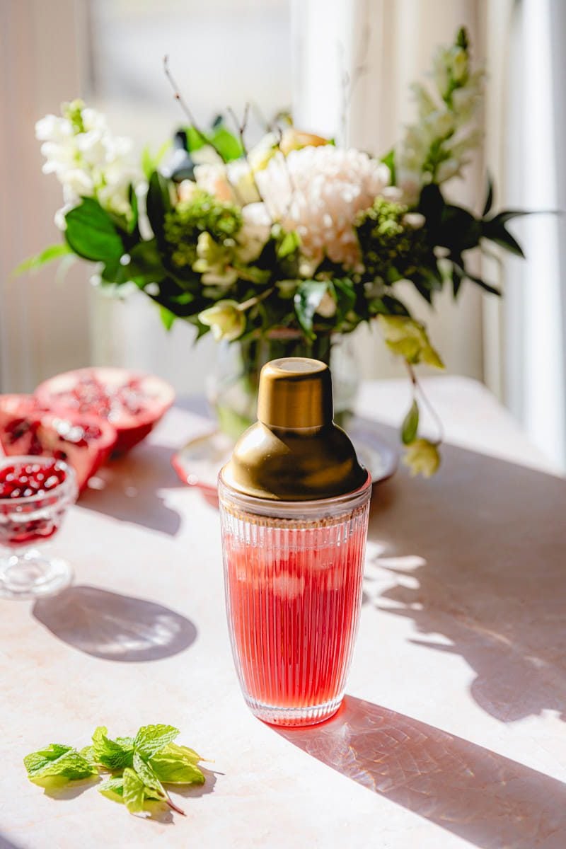 All pomegranate martini ingredients in a cocktail shaker.